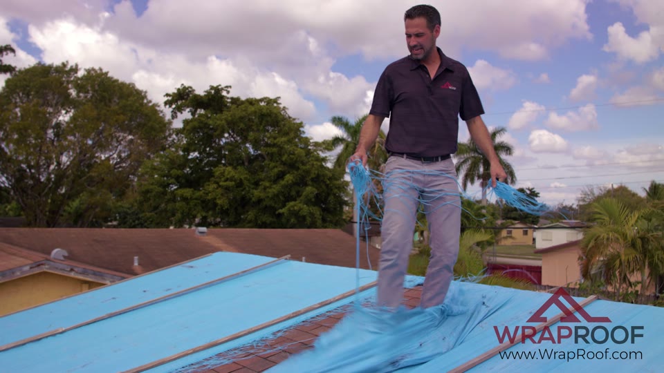 Installer rolling Wraproof membrane into place across a roof deck